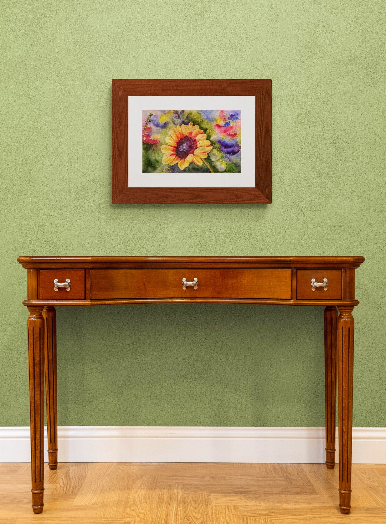Sunflower for Peace colorful watercolor painting on green wall above credenza.